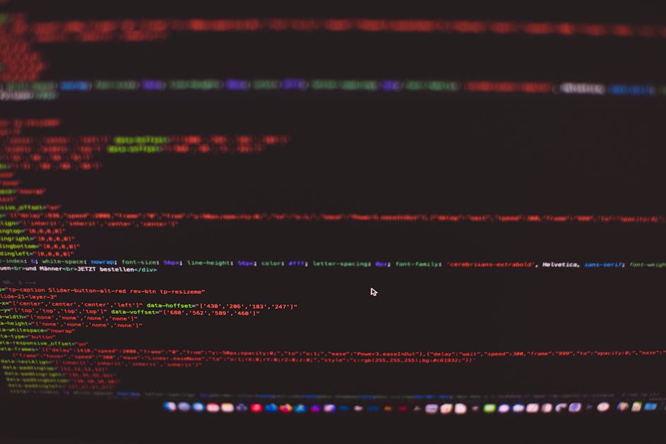 Close-up image of a computer screen displaying lines of colorful code, including red, green, blue, and purple text on a dark background. The code appears to be HTML or CSS, with visible tags, attribut