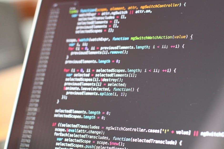 Close-up image of a computer screen displaying lines of colorful code, including red, green, blue, and purple text on a dark background. The code appears to be HTML or CSS, with visible tags, attribut